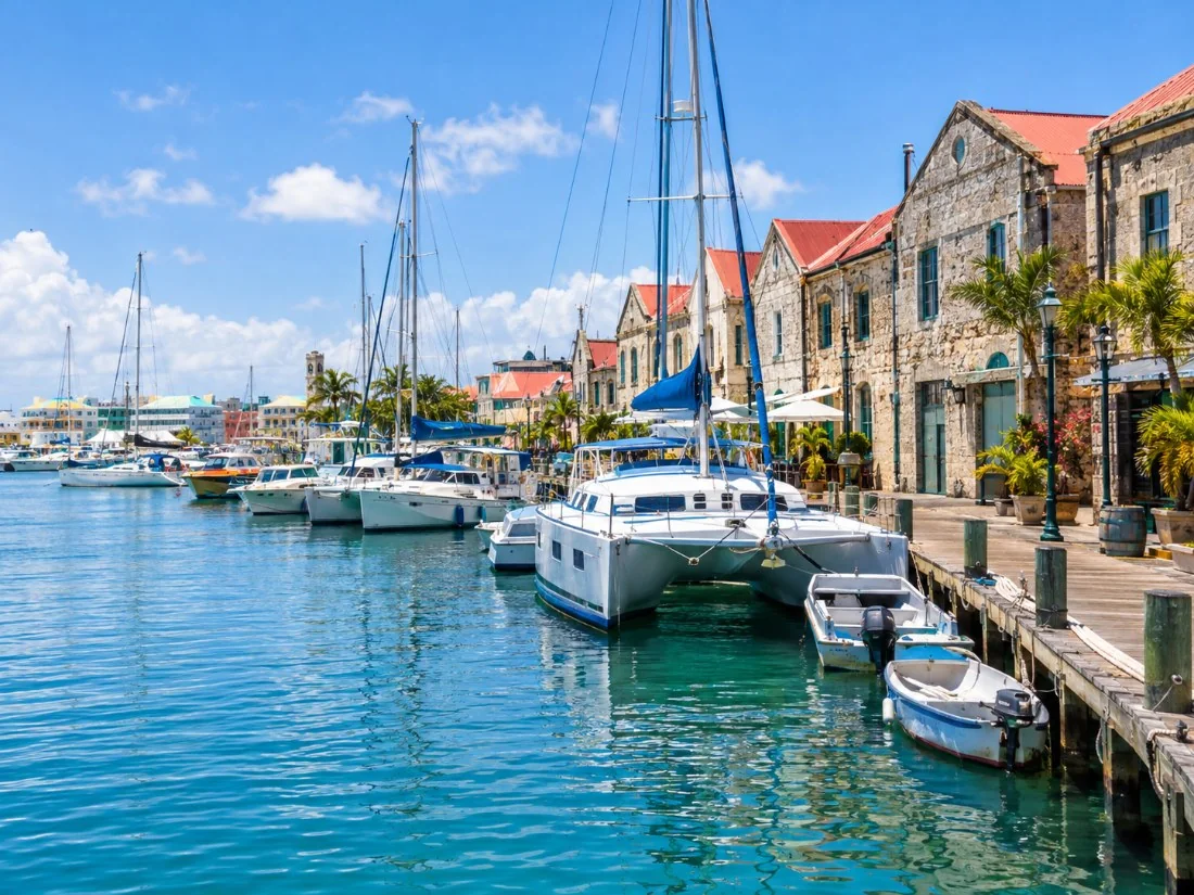 Katamarane und kleine Boote vor Anker entlang des Careenage in Bridgetown neben alten Steinspeichern